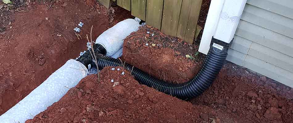 A French drain is installed at a property near Evans, GA to redirect water flow.